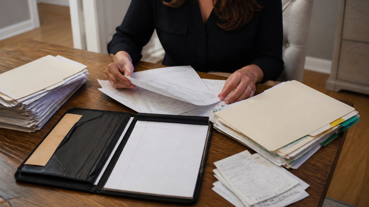 Person organizing financial and legal documents for a first meeting family lawyer consultation on a desk